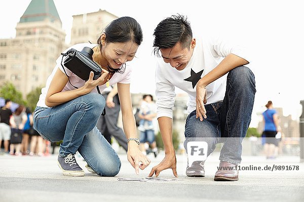 Touristenpaar  das auf den Bürgersteig schaut  auf Sofortfilmaufnahmen  The Bund  Shanghai  China