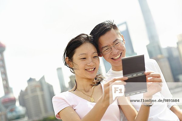 Touristenpaar beim Betrachten von Sofortbildern  The Bund  Shanghai  China