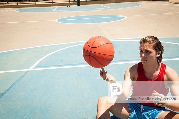 Junger Basketballspieler spinnt Ball auf Finger