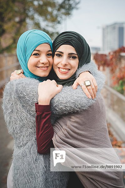 Porträt von zwei jungen Freundinnen  die sich auf dem Parkweg umarmen