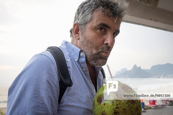 Mann trinkt frischen Kokossaft  Ipanema Beach  Rio de Janeiro  Brasilien