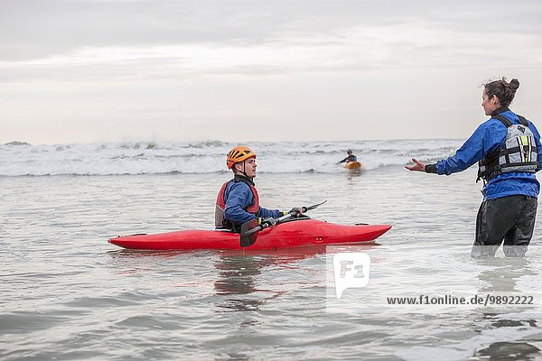 Female instructor helping young man in sea kayak