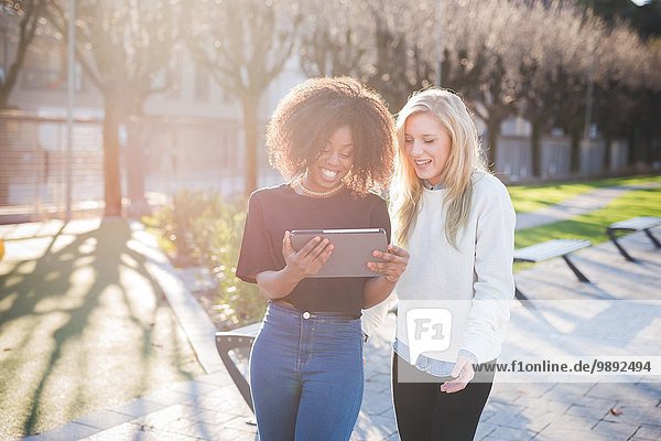 Zwei junge Freundinnen im Park beim Betrachten des digitalen Tabletts  Como  Italien
