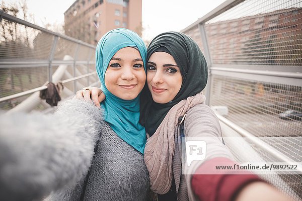 Zwei Freundinnen auf der Fußgängerbrücke nehmen Selfie