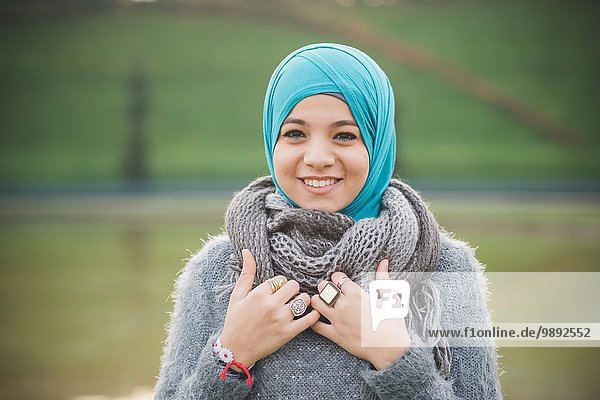 Porträt einer jungen Frau im Park mit türkisfarbenem Hijab