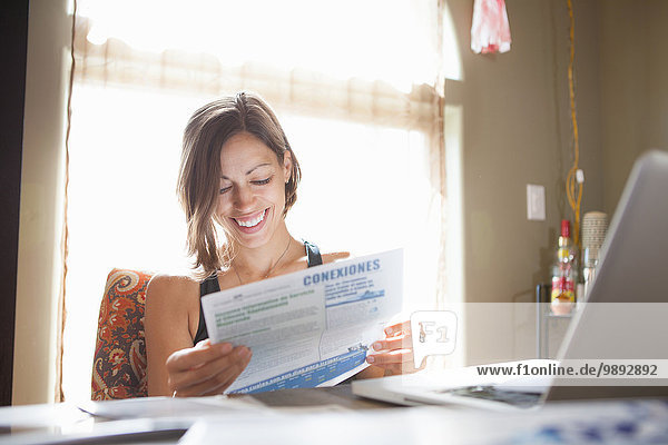 Woman working at desk at home reading paperwork