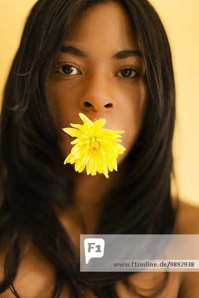 Junge Frau posiert mit Blume im Mund