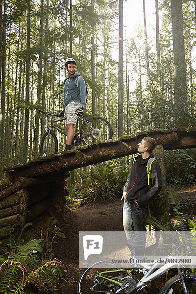 Zwei junge Männer mit Mountainbikes  im Wald