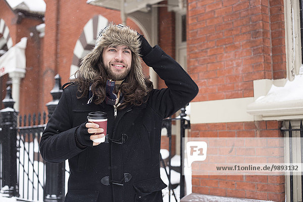 Young man strolling along street drinking takeaway coffee
