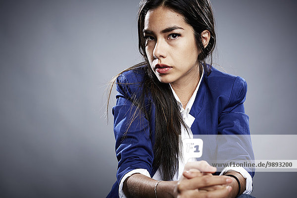 Porträt einer jungen Frau mit umklammerten Händen und ernsthaftem Ausdruck