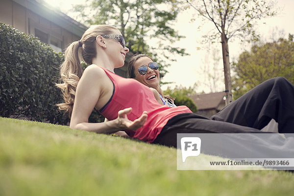 Two women relaxing on grass chatting low angle view