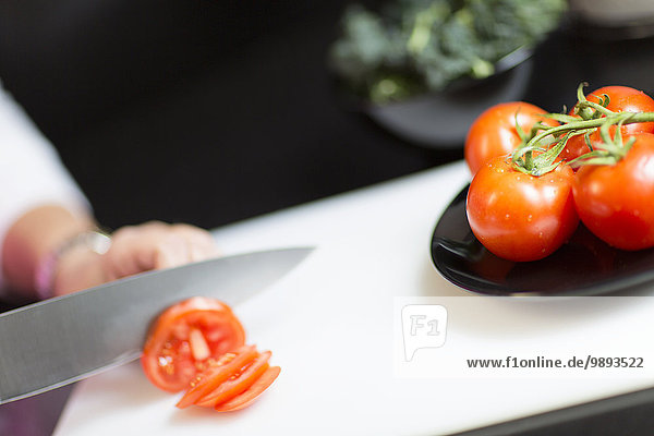 Slicing tomatoes  focus on knife and tomatoes