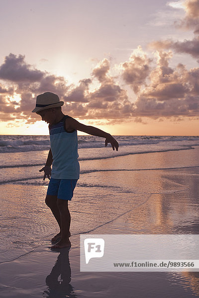 Junge beim Erkunden am Strand bei Sonnenuntergang