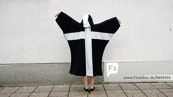 Rückansicht junge Frau junge Frauen überqueren Wand Mantel weiß schwarz Kapuzenjacke Bewegung Kreuz