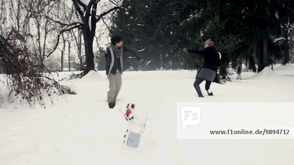 Couple Playing in Snow Near Snow Man