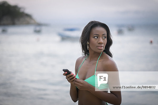 Mexiko  junge Frau mit Handy am Strand