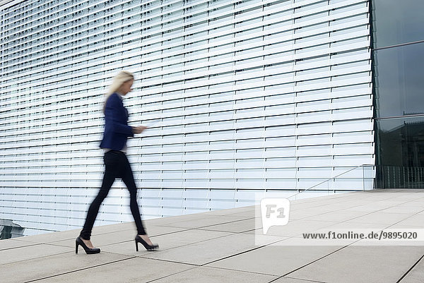 Geschäftsfrau beim Gehen mit digitalem Tablett