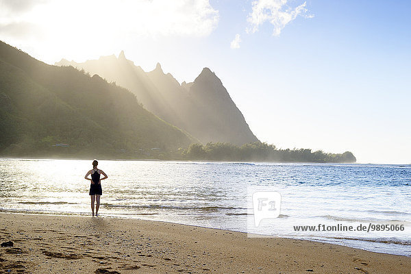 USA  Hawaii  Hanalei  woman standing on Haena Beach  View to Na Pali Coast in the evening light