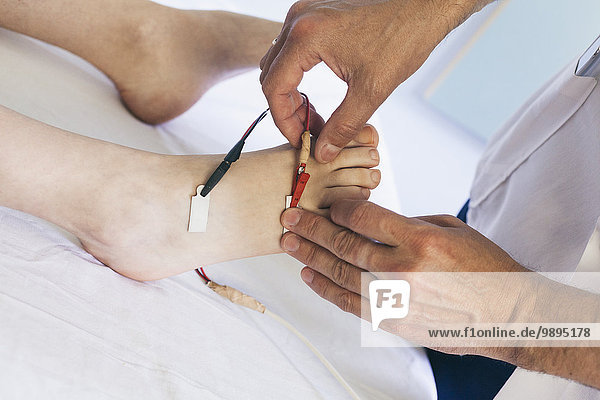 Chiropraktiker bei der Durchführung einer Fußelektrotherapie