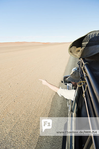 Namibia  Namib Wüste  Namib Naukluft Park  Sossusvlei  Mann im Auto  der mit dem Finger zeigt