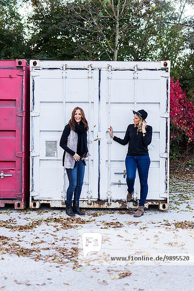 Zwei Freundinnen stehen vor einem Container.