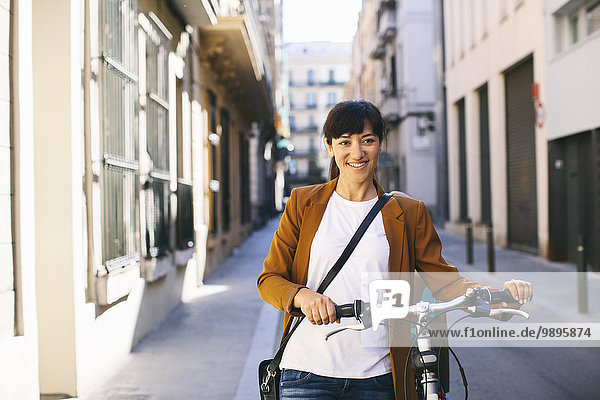 Spain  Barcelona  smiling woman with bicycle in the city