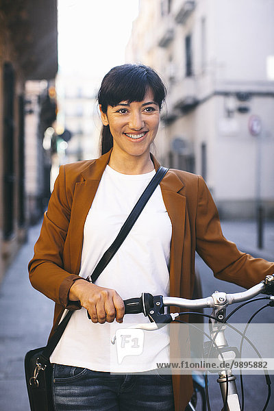 Spanien  Barcelona  lächelnde Frau mit Fahrrad in der Stadt