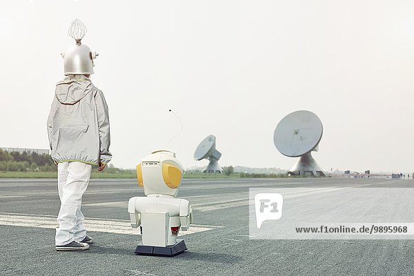 Junge verkleidet als Raumfahrer mit Roboter