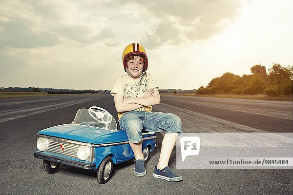 Smiling boy with pedal car on race track