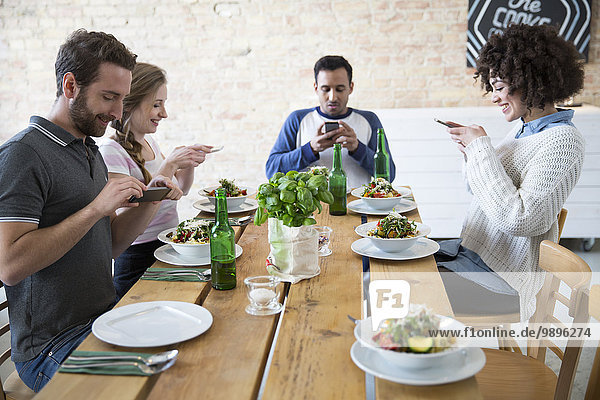 Friends sitting together at dining table posting food
