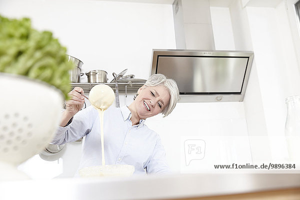 Reife Frau beim Backen in der Küche