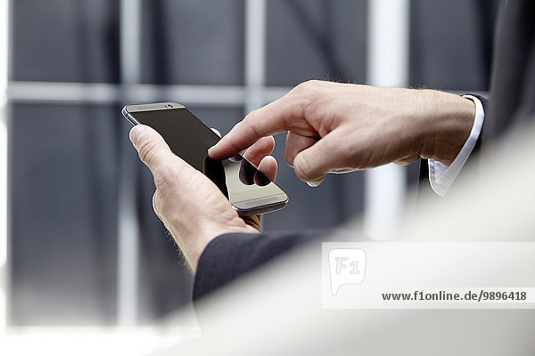 Hands of businessman touching screen of his smartphone