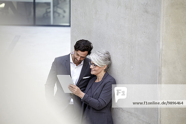 Two business people with digital tablet in modern architecture