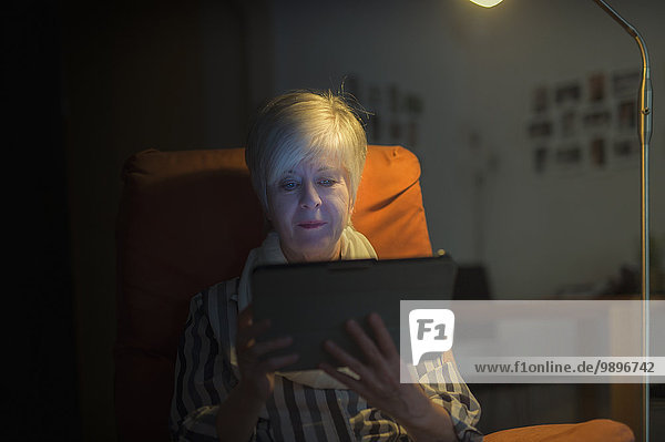 Seniorin im Sessel sitzend mit digitalem Tablett