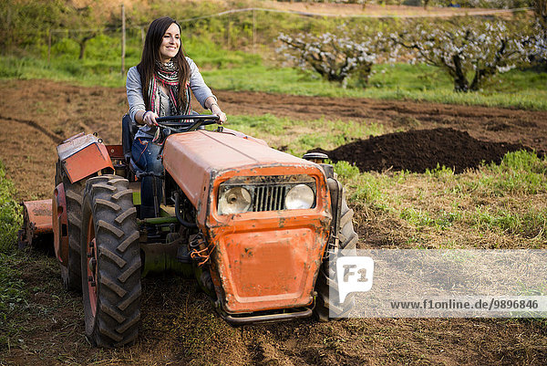 Bäuerin fährt einen alten Traktor durch ein Feld