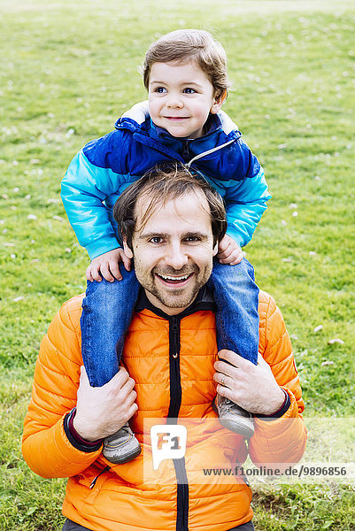 Glücklicher Vater mit Sohn auf den Schultern im Park