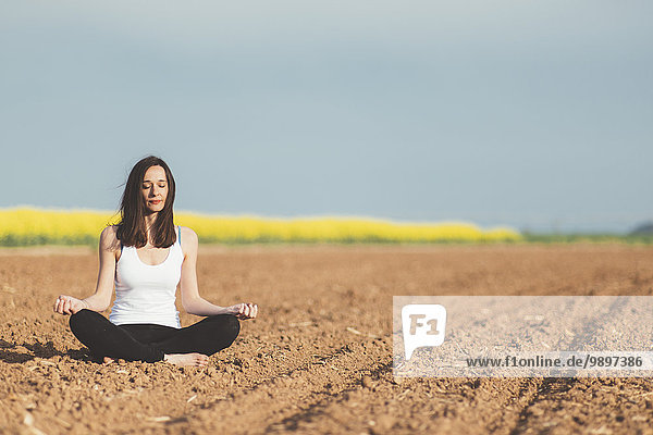 Frau meditiert auf einem Feld
