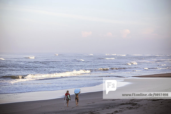 Indonesien  Bali  zwei Frauen mit Surfbrettern am Strand