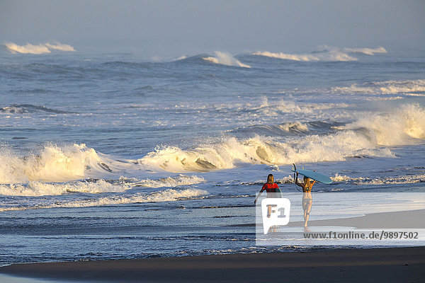 Indonesien  Bali  zwei Frauen mit Surfbrettern am Meer