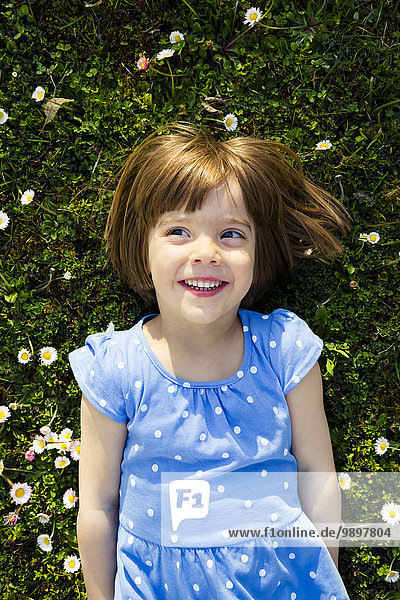 Portrait of smiling little girl lying on a meadow