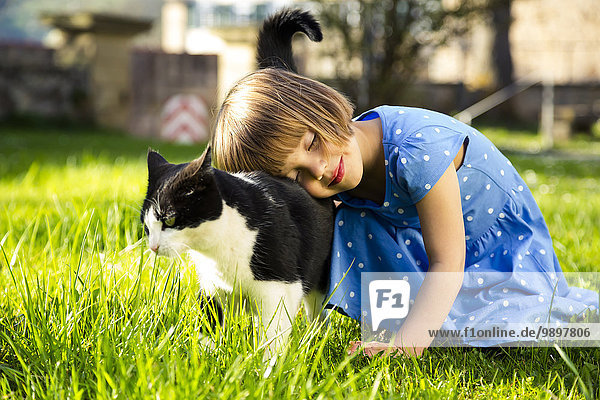 Kleines Mädchen mit Katze auf einer Wiese