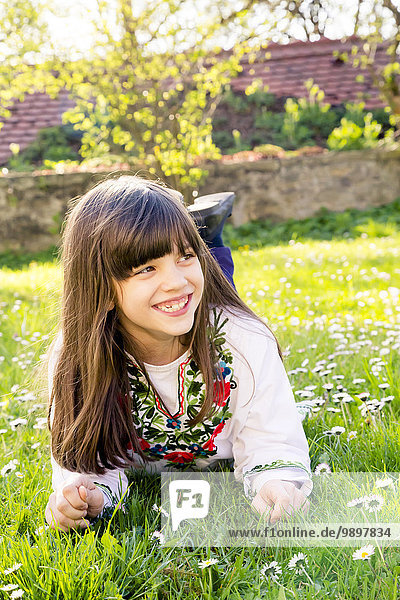 Porträt eines lächelnden Mädchens auf einer Wiese liegend