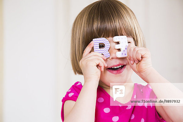 Portrait of smiling little girl peeking through two wooden letters