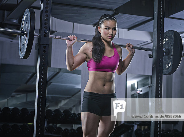 Young woman doing weightlifting with barbell