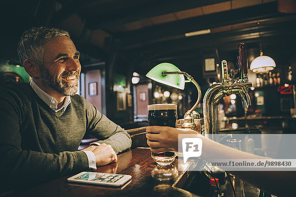 Smiling man sitting at counter of a pub