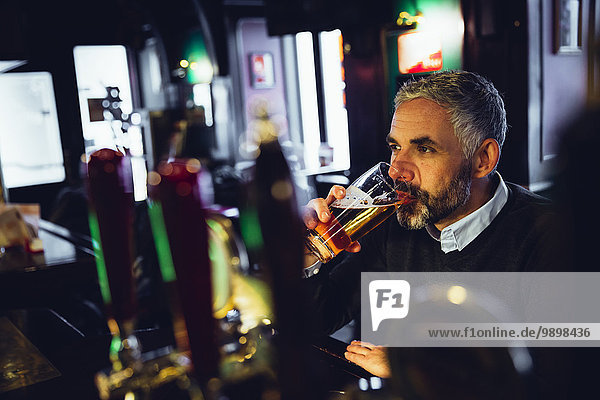 Man sitting at counter of a pub drinking beer
