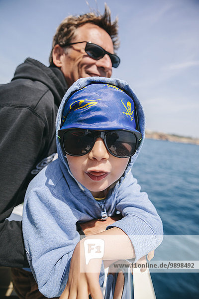 Spanien  Mallorca  kleiner Junge mit Sonnenbrille und Piraten-Kopftuch und sein Onkel auf einem Segelboot