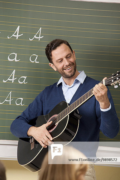 Lehrer beim Gitarrespielen im Klassenzimmer