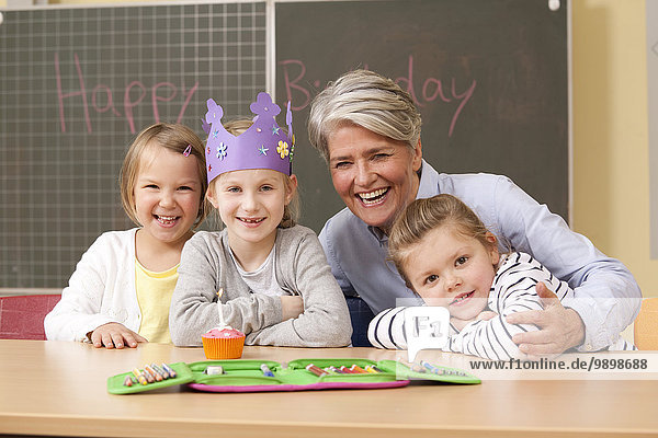 Porträt einer glücklichen Lehrerin und Schülerin zum Geburtstag im Klassenzimmer