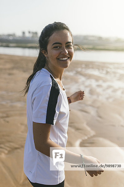 Spanien  Gijon  sportliche junge Frau lächelnd am Strand